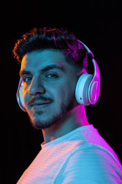 Siyah stüdyo arka planında neon ışıklı genç adam portresi. İnsan duyguları kavramı, yüz ifadesi, gençlik, satış, reklam.