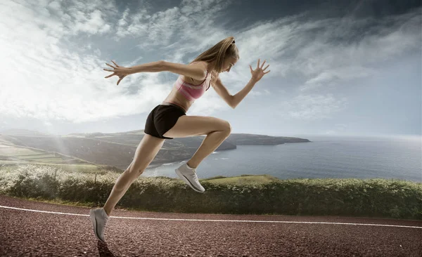 Corredor profesional, corredora en la carretera y el fondo del cielo. Atleta en forma caucásica practicando, entrenando excitado — Foto de Stock