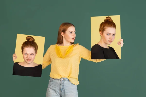 Young red headed girl holding her portraits isolated over green studio background with copyspace for ad. Concept of beauty, fashion. — Stockfoto