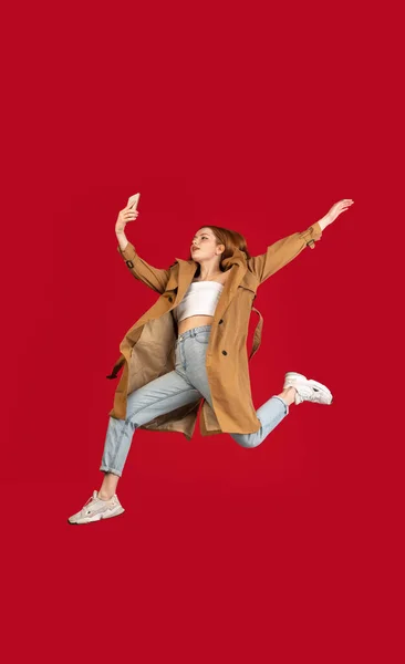 若い幸せな女の子は広告のためのコピースペースと赤いスタジオの背景の上に隔離ジャンプします。美しさ、ファッションの概念. — ストック写真