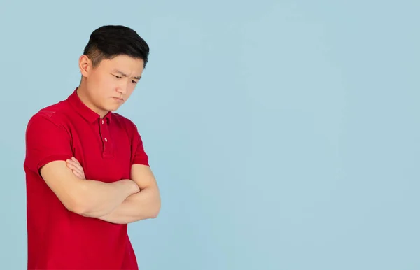 Mavi stüdyo arka planında izole edilmiş Asyalı genç adamın yarım boy portresi. İnsan duyguları kavramı — Stok fotoğraf
