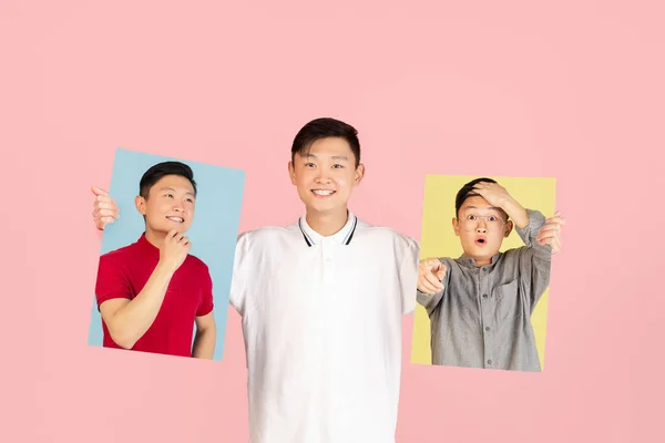 One Asian young man holding his portraits isolated on pink studio background. Concept of human emotions. — Stockfoto