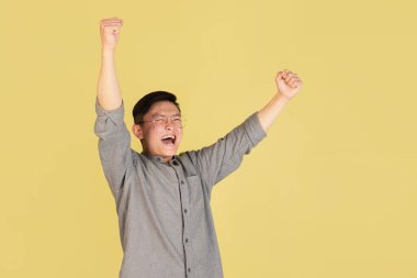 Sarı stüdyo arka planında Asyalı genç adam portresi. İnsan duyguları kavramı, yüz ifadesi, gençlik, satış, reklam.