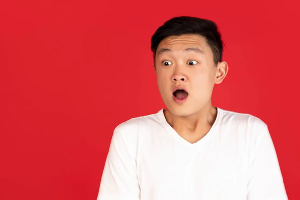 Close-up portrait of Asian young man isolated on red studio background. Concept of human emotions, facial expression, youth, ad. — Stockfoto