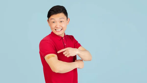 Half-length portrait of Asian young man isolated on blue studio background. Concept of human emotions, COVID vaccine — Stockfoto