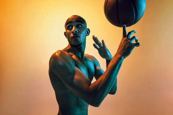 Handsome african-american male basketball player training in neon light on orange background. —  Fotos de Stock