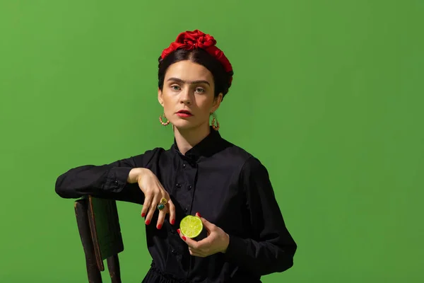 Close-up young beautiful woman in image of famous painter, artist Frida Kahlo on green background. Retro style, comparison of eras concept. — 图库照片