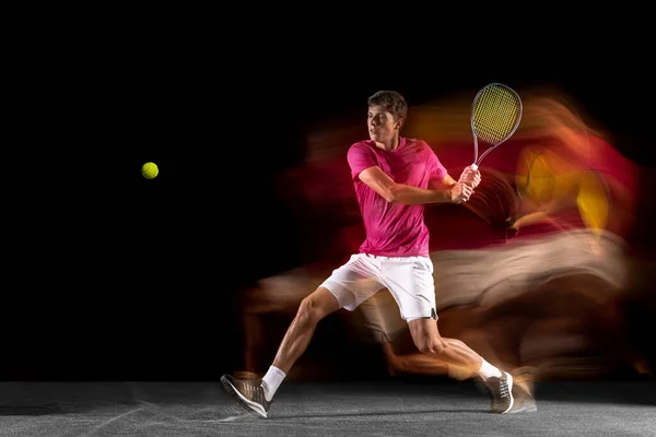 One man, male tennis player training isolated in mixed neon light on dark background. Concept of sport, team competition. — Photo
