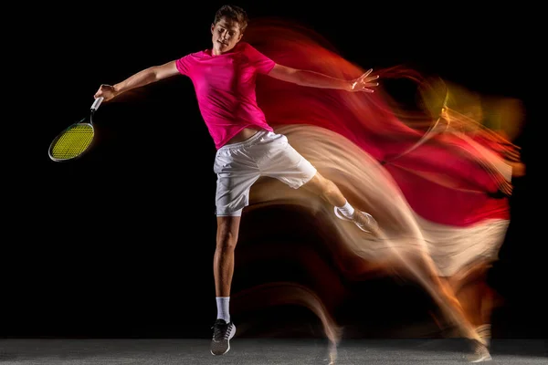 One man, male tennis player training isolated in mixed neon light on dark background. Concept of sport, team competition. — Stock Fotó