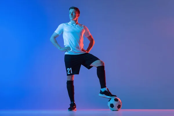 Ganztägiges Porträt eines Fußballprofis, der isoliert auf einem blau-rosa Hintergrund im Neonlicht steht. Konzept von Sport, Schönheit. — Stockfoto