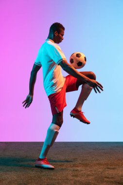 Bir Afrikalı, profesyonel futbolcu eğitimi neon ışıklarıyla izole edilmiş mavi bir arka planda..