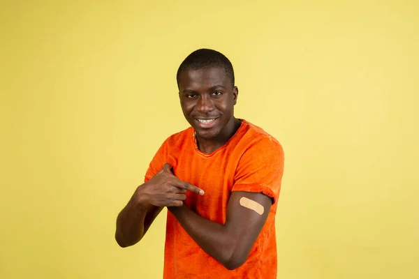 Retrato de un hombre sonriendo después de recibir una vacuna. Varón africano mostrando brazo con vendaje después de recibir la vacunación. — Foto de Stock