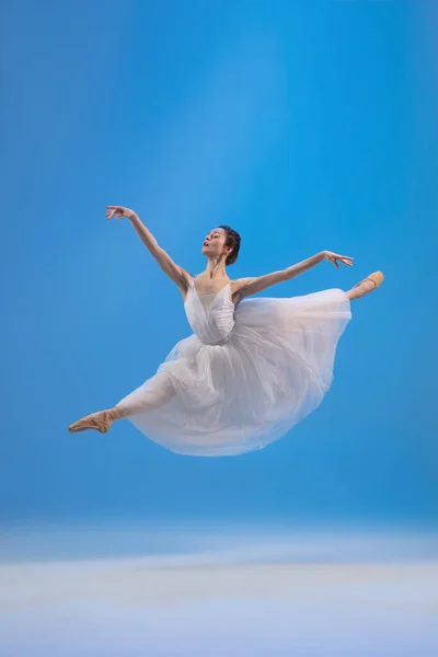 Fiatal és kecses balett táncos elszigetelt kék stúdió háttérben. Művészet, mozgás, cselekvés, rugalmasság, inspiráció. — Stock Fotó