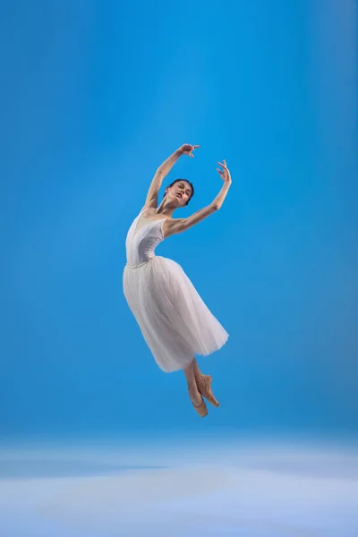 Fiatal és kecses balett táncos elszigetelt kék stúdió háttérben. Művészet, mozgás, cselekvés, rugalmasság, inspiráció. — Stock Fotó