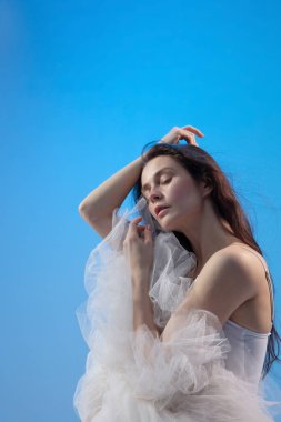 Mavi stüdyo arka planında oturan yorgun balerin.