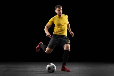 Güçlü, sahanın üstünde uçuyor. Genç futbol, futbol oyuncusu, siyah stüdyo arka planında izole hareket .