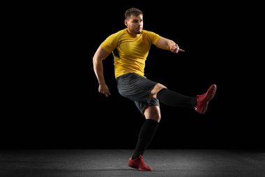 Güçlü, sahanın üstünde uçuyor. Genç futbol, futbol oyuncusu, siyah stüdyo arka planında izole hareket .