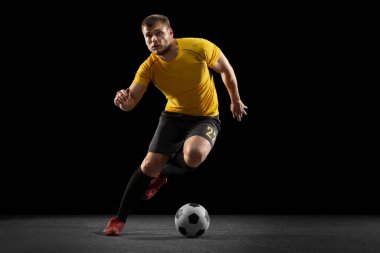 Güçlü, sahanın üstünde uçuyor. Genç futbol, futbol oyuncusu, siyah stüdyo arka planında izole hareket .