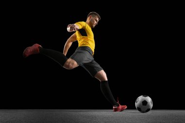Güçlü, sahanın üstünde uçuyor. Genç futbol, futbol oyuncusu, siyah stüdyo arka planında izole hareket .
