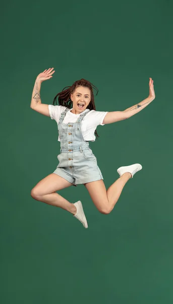 Jumping high, stylish. Caucasian young womans portrait isolated on green studio background with copyspace for ad. — Stock Photo, Image