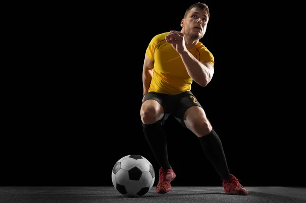 Poderoso, voando acima do campo. Jovem futebol, jogador de futebol em ação, movimento isolado no fundo do estúdio preto . — Fotografia de Stock