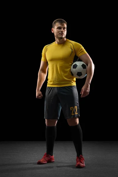 Professionele Kaukasische voetbal voetballer geïsoleerd op zwarte studio achtergrond. — Stockfoto