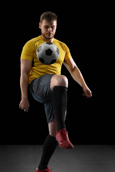 Krachtig, vliegend boven het veld. Jong voetbal, voetballer in actie, beweging geïsoleerd op zwarte studio achtergrond . — Stockfoto