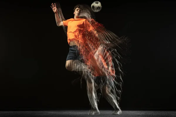 Один кавказский футболист движется и действует в смешанном свете на темном фоне. — стоковое фото
