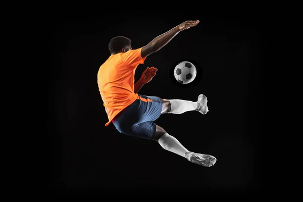 Young African football soccer player playing isolated on black background. Concept of sport, movement, energy and dynamic. — Stock Photo, Image