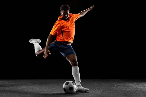 Jovem jogador de futebol africano jogando isolado em fundo preto. Conceito de desporto. — Fotografia de Stock