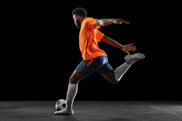 Jovem jogador de futebol africano jogando isolado em fundo preto. Conceito de desporto. — Fotografia de Stock