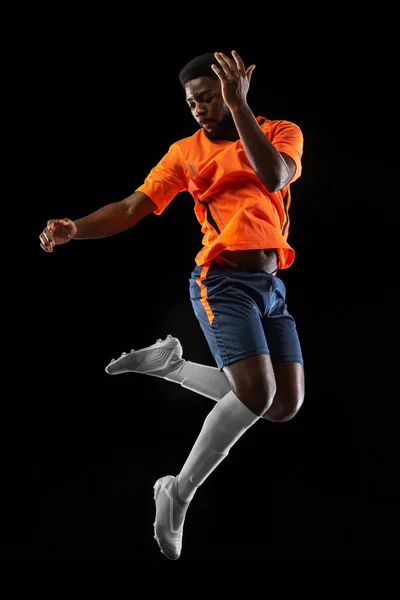 Um jogador de futebol africano jogando isolado em fundo preto. Conceito de desporto. — Fotografia de Stock