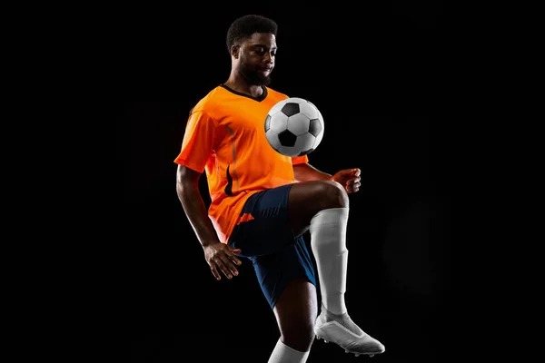 Jogador de futebol afro-americano jogando isolado em fundo preto. Conceito de desporto. — Fotografia de Stock