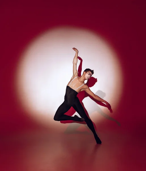 Ballerino che balla sullo sfondo rosso dello studio. Design moderno. Luce concettuale colorata contemporanea come sole nascente in Giappone. — Foto Stock