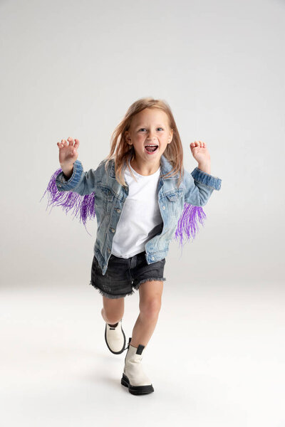 Улыбающаяся милая девушка, бегающая по белому фоне студии. Кавказская модель с длинными вытянутыми волосами в летнем платье.