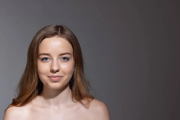 Portret van een jong vrouwelijk modemodel geïsoleerd op een grijze studioachtergrond. Mooie blanke vrouw met goed onderhouden huid. — Stockfoto