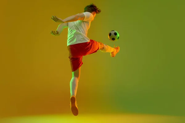 年轻的高加索男子，男子足球运动员在霓虹灯下被隔离在深蓝色粉红的背景下训练 — 图库照片