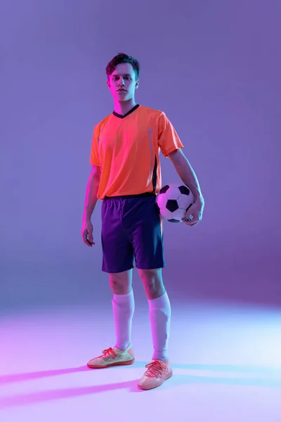 Full-length portret van professionele voetballer geïsoleerd op gradiënt blauw roze achtergrond in neon licht. Begrip sport, schoonheid. — Stockfoto