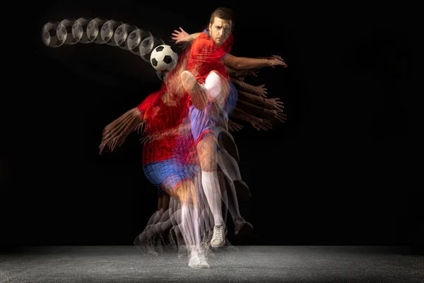 Não pare de se mexer. Jovem jogador de futebol caucasiano jogando em movimento em luz mista sobre fundo escuro. — Fotografia de Stock