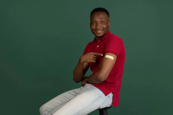 Portrait d'un homme souriant après avoir reçu un vaccin. Homme africain montrant un bras avec bandage après avoir été vacciné. — Photo