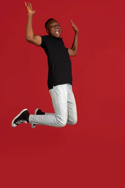 Skoki wysoko, stylowo. Afrykański młody mężczyzna portret odizolowany na czerwonym tle studio z copyspace dla reklamy. — Zdjęcie stockowe