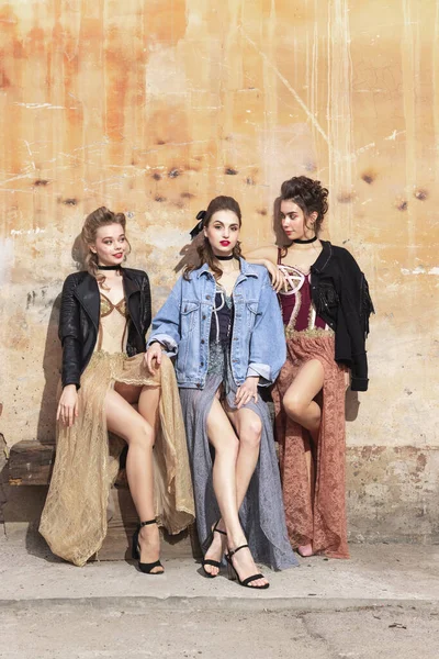 Pretty women in vintage 20s dresses. Young girls in art action sitting together and posing on wall background. — Stock Photo, Image