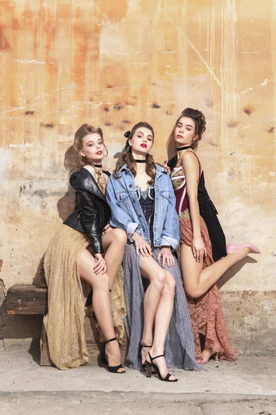 Pretty women in vintage 20s dresses. Young girls in art action sitting together and posing on wall background. — Stock Photo, Image