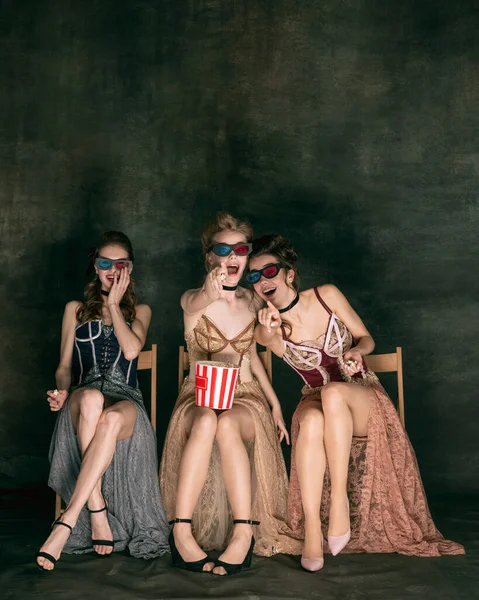 Mooie vrouwen in oude jurken van in de 20. Jonge meisjes in de kunst actie zitten samen en poseren op de muur achtergrond. — Stockfoto