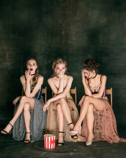 Mooie vrouwen in oude jurken van in de 20. Jonge meisjes in de kunst actie zitten samen en poseren op de muur achtergrond. — Stockfoto