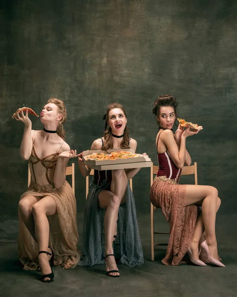 Mooie vrouwen in oude jurken van in de 20. Jonge meisjes in de kunst actie zitten samen en poseren op de muur achtergrond. — Stockfoto