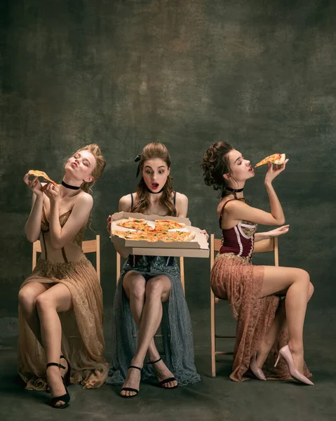 Mulheres bonitas em vestidos vintage dos anos 20. Meninas jovens em ação de arte sentado juntos e posando no fundo da parede. — Fotografia de Stock