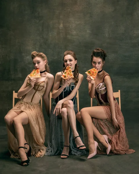 Красиві жінки в вінтажних сукнях 20-х років. Молоді дівчата в мистецькій дії сидять разом і позують на фоні стіни . — стокове фото