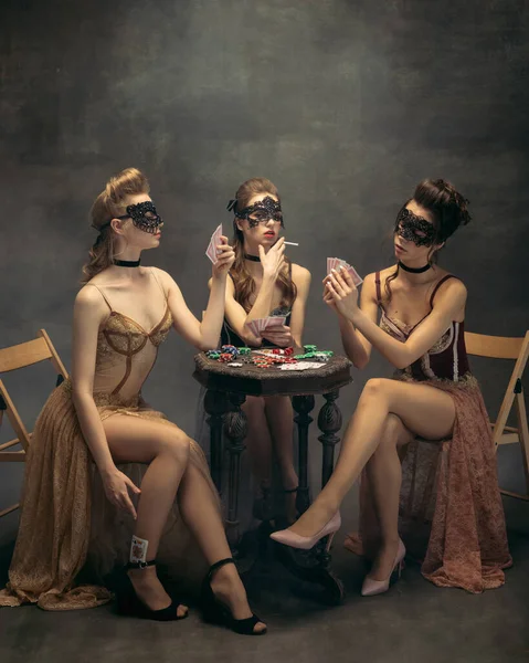 Ładne kobiety w sukienkach z lat 20-tych. Młode dziewczyny w akcji sztuki siedzi razem i pozowanie na tle ściany. — Zdjęcie stockowe