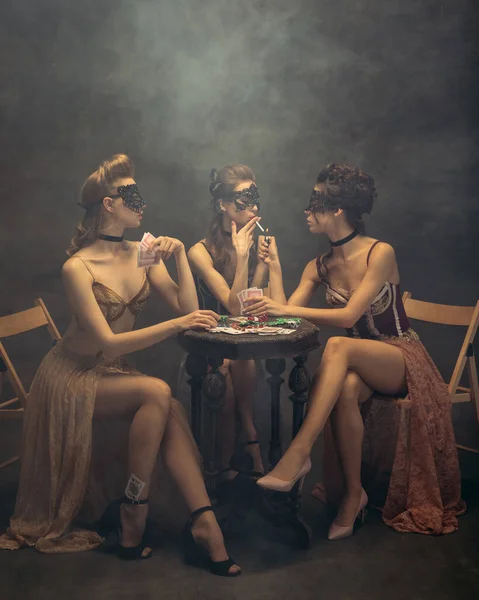 Ładne kobiety w sukienkach z lat 20-tych. Młode dziewczyny w akcji sztuki siedzi razem i pozowanie na tle ściany. — Zdjęcie stockowe